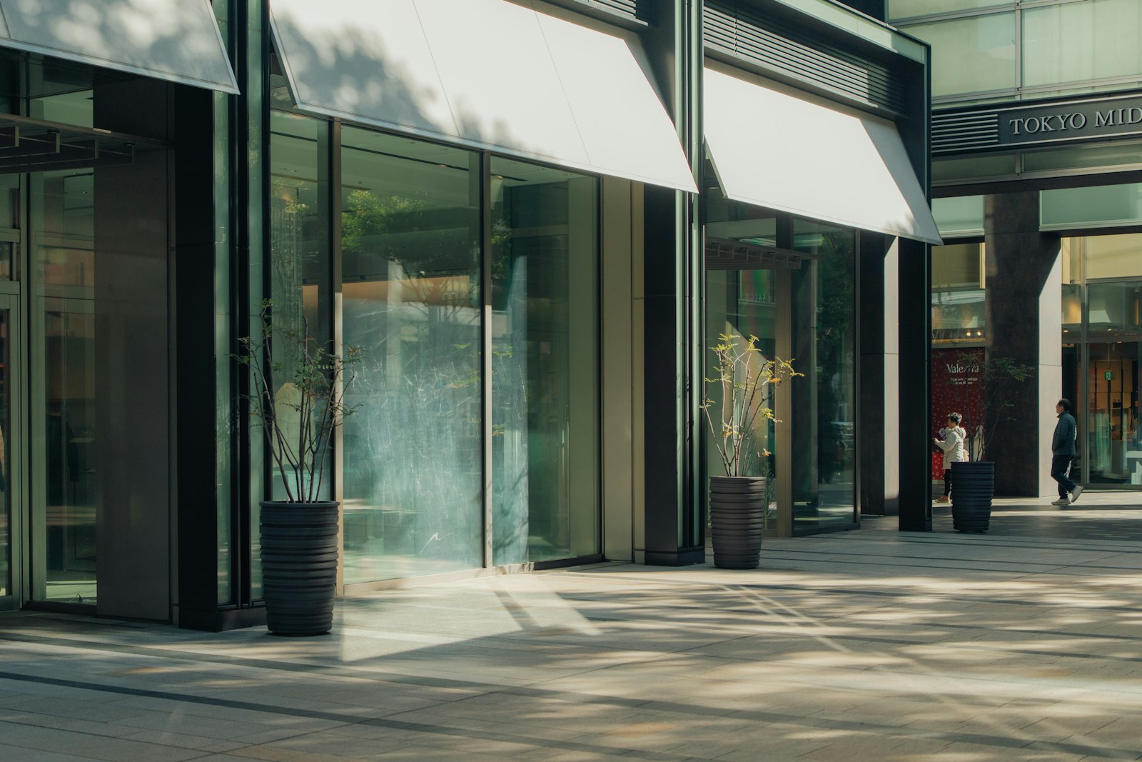 Floor-to-ceiling commercial storefront glass with dark metal frames and white awnings